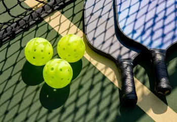 Pickleballs and paddles on the ground on a pickleball court