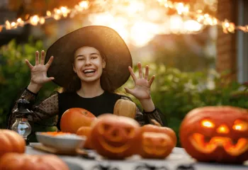 Teenage girl sitting at a table with jack-o-lanterns