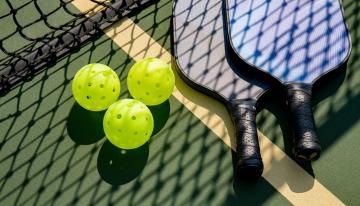 Pickleballs and paddles on the ground on a pickleball court