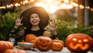 Teenage girl sitting at a table with jack-o-lanterns